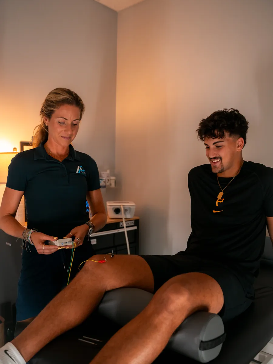 Athlete Pro provider and a smiling patient talking at the start of a treatment session, with therapy leads attached to the patient's knee
