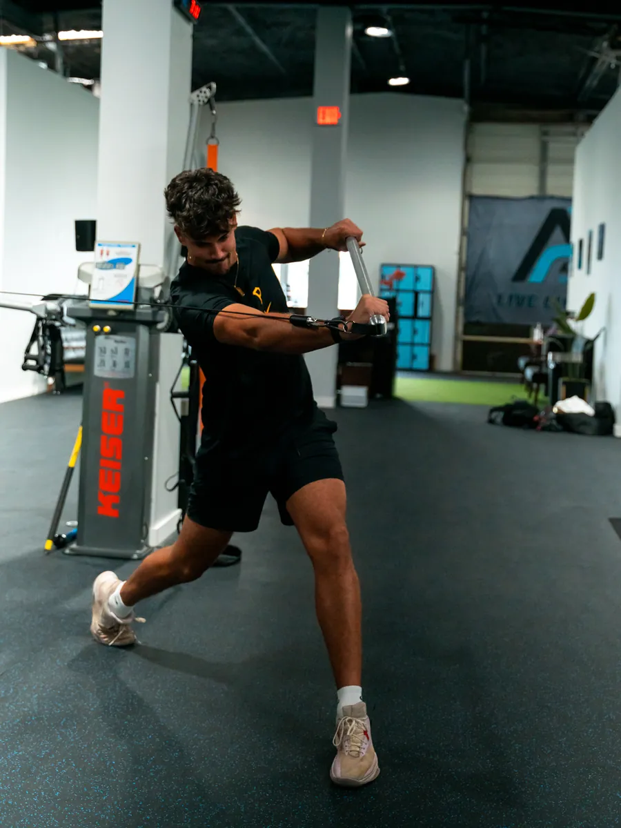 Athlete performing a cable rotation exercise on a resistance machine in the Athlete Pro training space