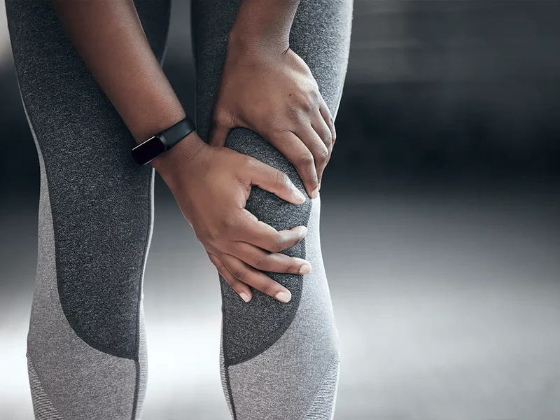 Close-up of hands gripping a sore knee joint