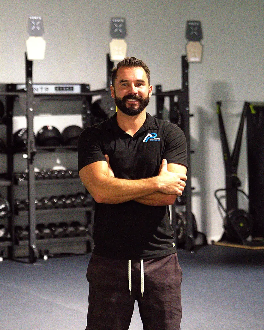 Taylor Holland, ATC, Owner of Athlete Pro Sports Medicine in Sarasota, FL, smiling in the clinic training area