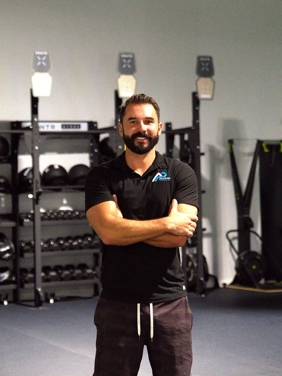 Taylor Holland, ATC, Owner of Athlete Pro Sports Medicine in Sarasota, FL, standing in the clinic training area