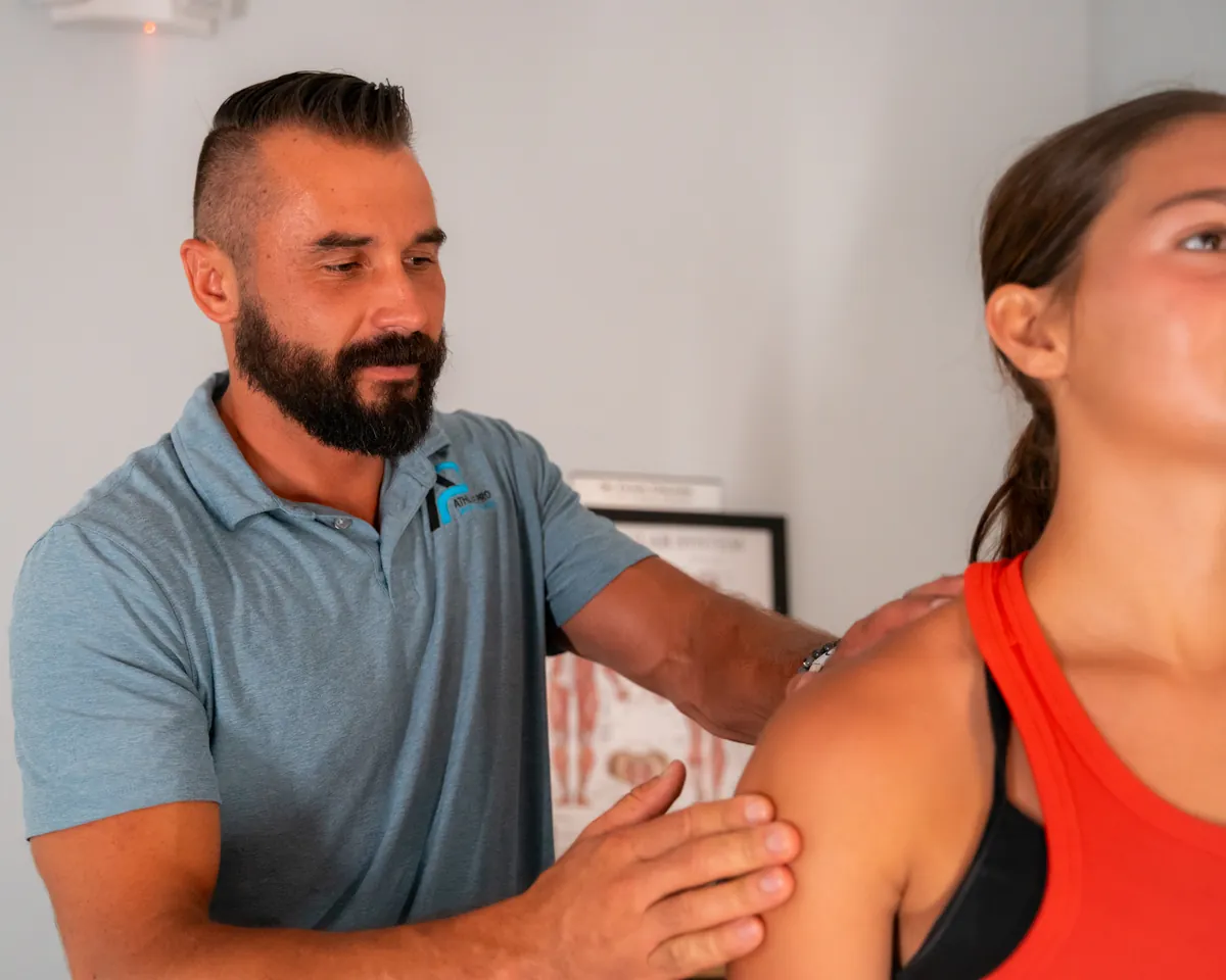 Athlete Pro provider using both hands on an athlete's shoulder during a hands-on treatment session